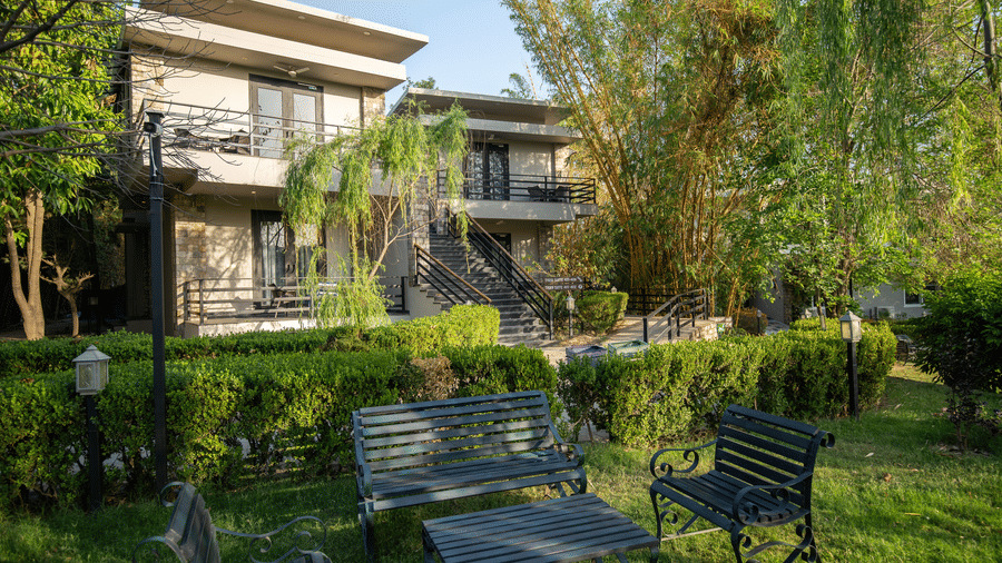 Lawn area of the resort building with a lush green garden and outdoor seating in the daytime at The Golden Tusk, Jim Corbett
