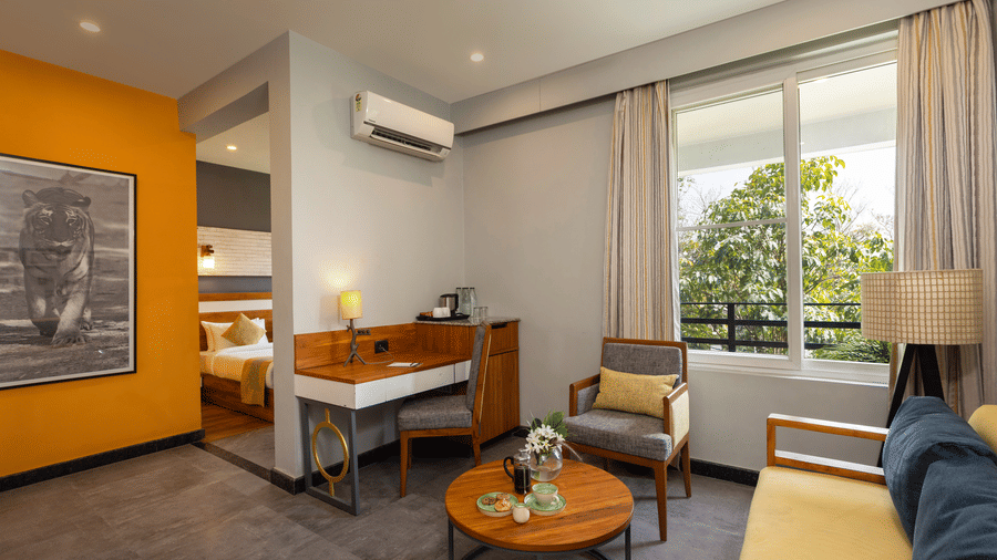 Pool View Suite with a desk, chairs, and a window with curtains at The Golden Tusk, Jim Corbett