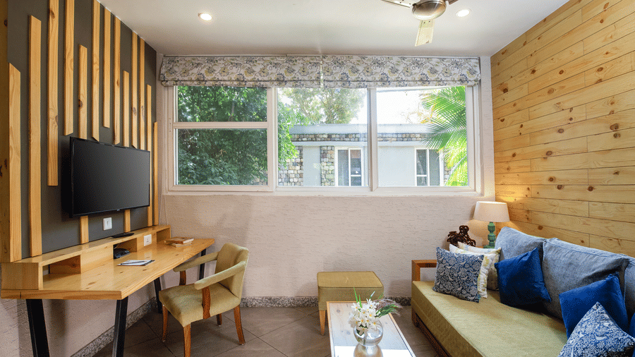 Villa Grande living space with a sofa, table, ceiling fan, and large windows  at The Golden Tusk, Jim Corbett