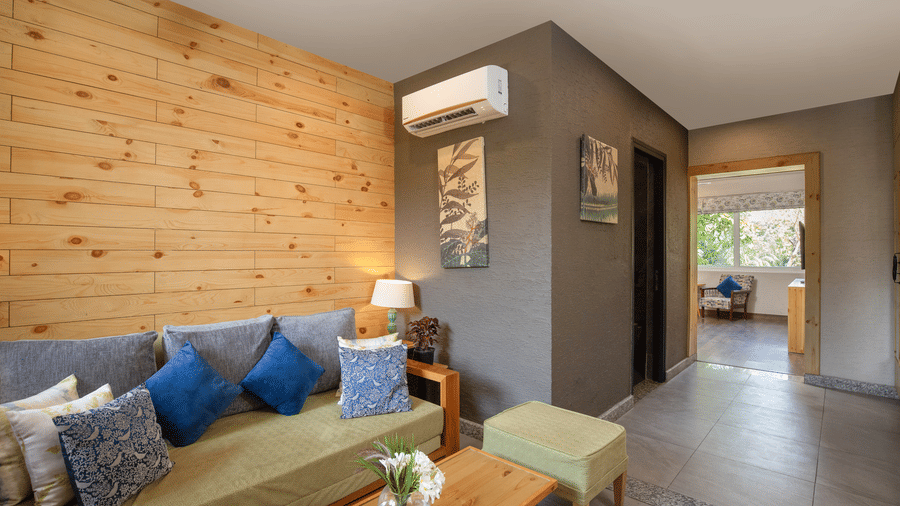 Villa Grande living room area with a couch, wooden accents, an air conditioning unit  at The Golden Tusk, Jim Corbett