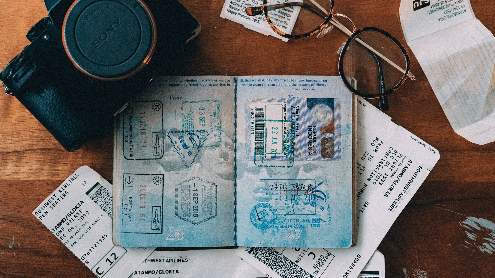 An open passport along with a camera glasses and other papers