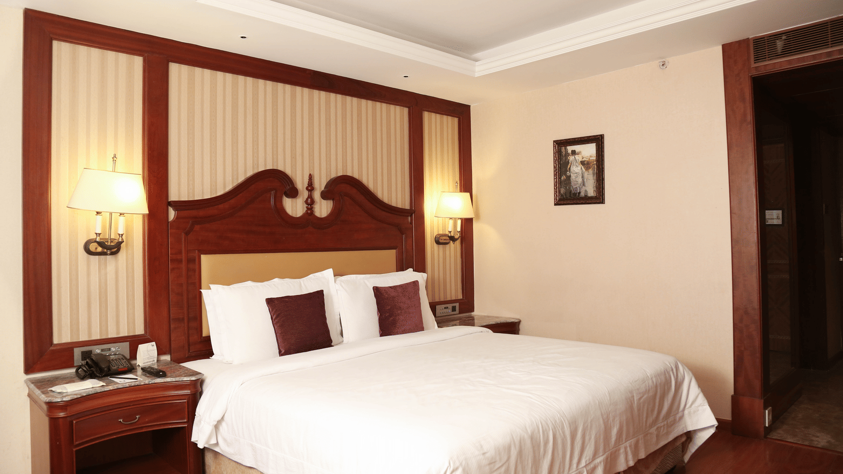 Spacious king bedroom with wooden flooring, warm lighting, and elegant interiors for comfortable day stays near Chennai airport | Hablis Hotel Chennai
