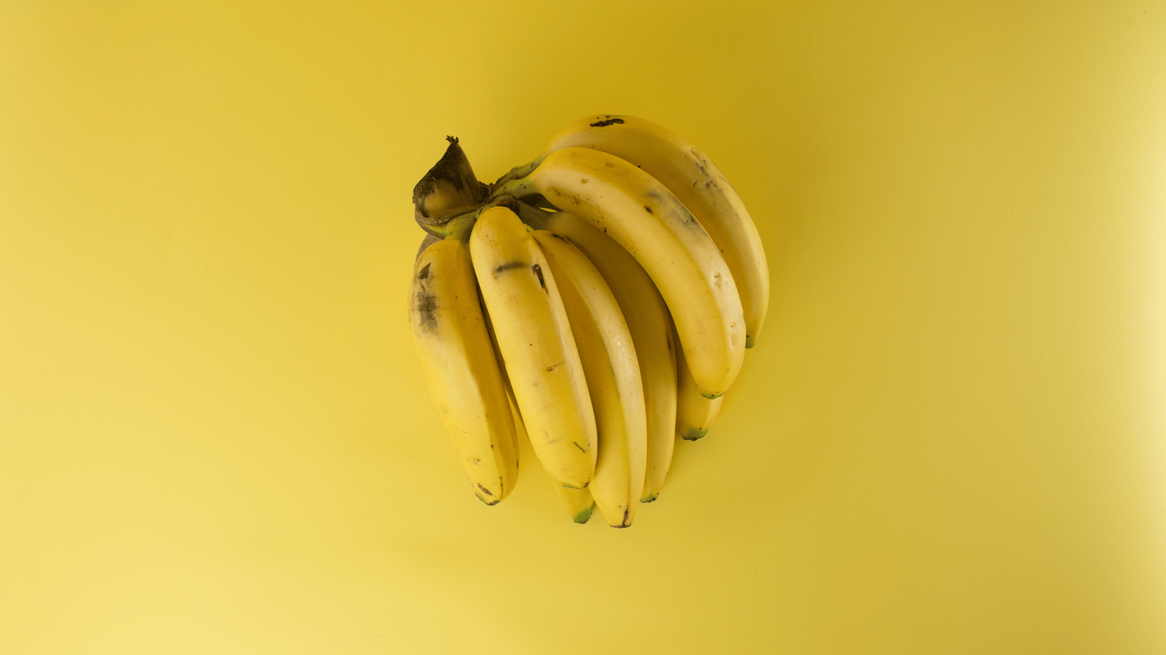 A small bunch of ripe yellow bananas showing a few dark spots