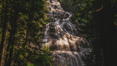 Water cascading down a mountain, with few rays of the sun falling over the water.