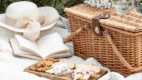 a hat, a book and a basket in a picnic setting