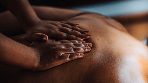 A masseuse giving a massage with both her hands to the back of a client who is sleeping on their chest at The Serai Bandipur.