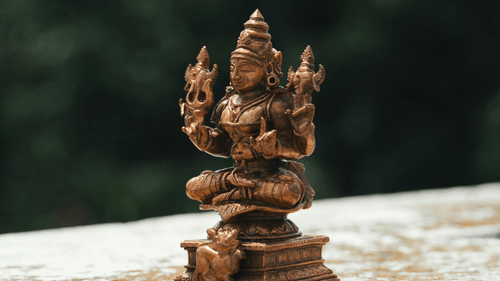 A small, carved statue of the Hindu deity Ganesha sits on a ledge outdoors.