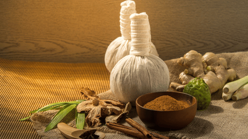 A couple of poultices placed together next to a small bowl containing powdery substance and dry spices around