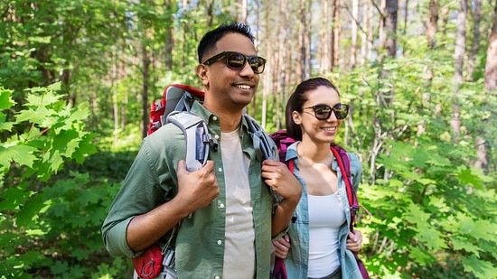 a man and a woman geared up for activities amidst lush green forest