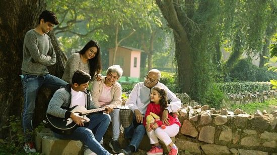 A family sitting in a area surrounded by trees and having fun