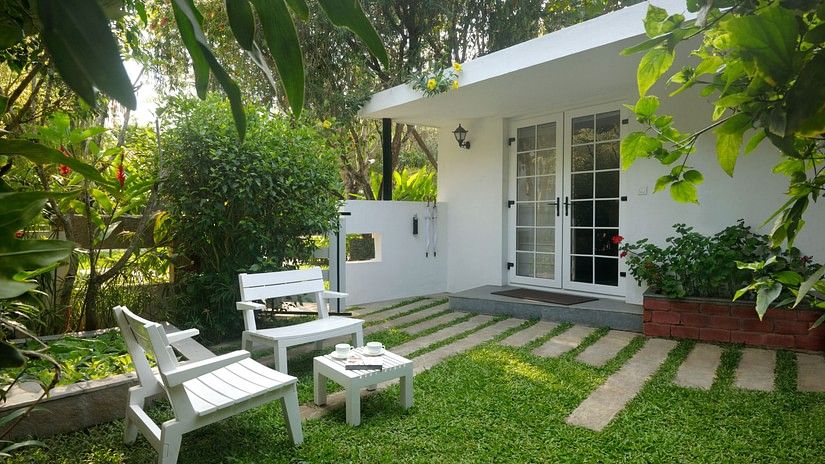 White outdoor seating arrangement in a garden with lush plants and a walking path