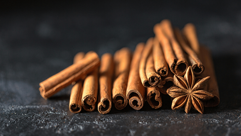 Image 8: Cinnamon sticks and star anise on dark textured surface, spices arranged, warm brown tones.