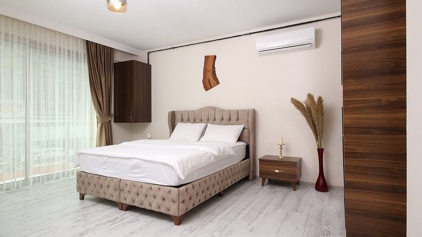 Room with bed, vase and dry flowers in it and a wall mounted ac above it