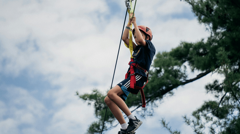 A person enjoying zipline against a clouded sky