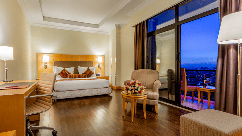 An overview of a room with a double bed, side tables, lamps and a study table - Ramada by Wyndham Addis, Addis Ababa