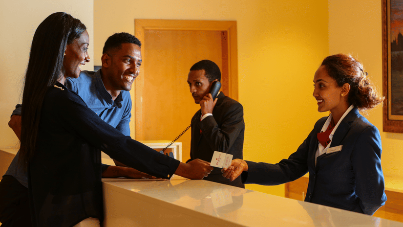 An overview of the reception area with a staff member speaking to two customers - Ramada by Wyndham Addis, Addis Ababa.