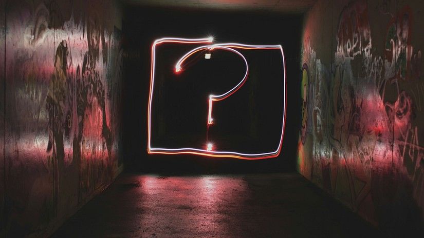 A question mark inside a box in neon with abstract art on either side