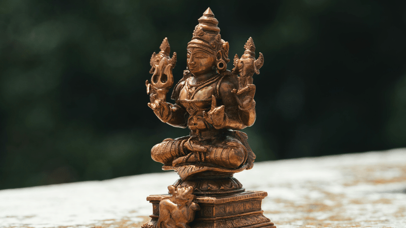 A small, carved statue of the Hindu deity Ganesha sits on a ledge outdoors.