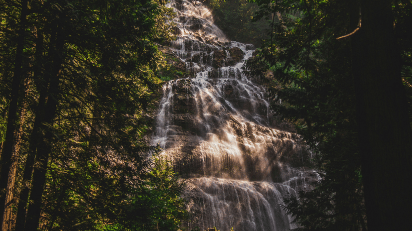 Water cascading down a mountain, with few rays of the sun falling over the water.