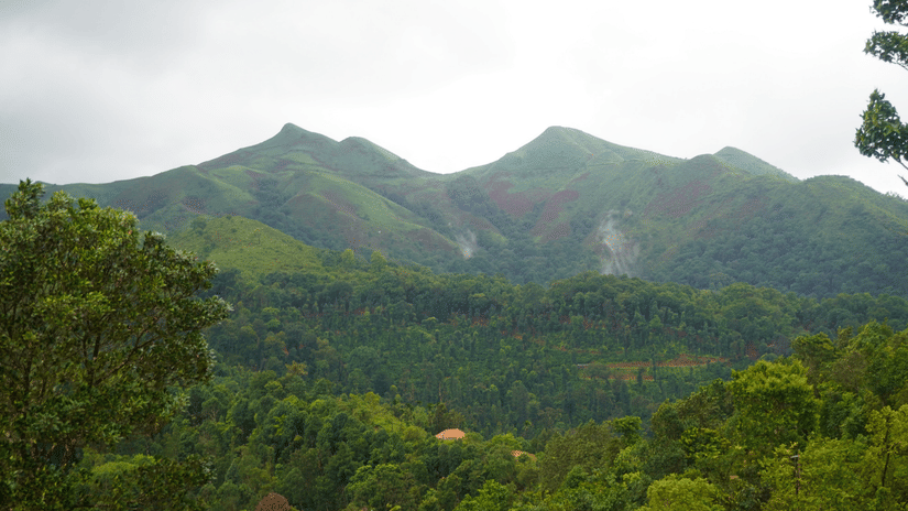 Mountains in Chikmagalur featuring lush slopes under a partially cloudy sky