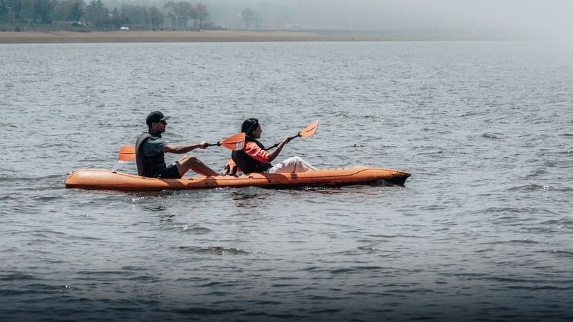 Two people kayaking in a river wearing life jackets.