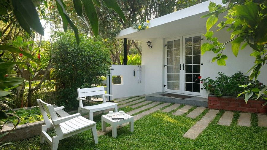 White outdoor seating arrangement in a garden with lush plants and a walking path