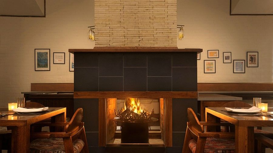 Cozy restaurant interior with a lit fireplace and dining tables ready for service.