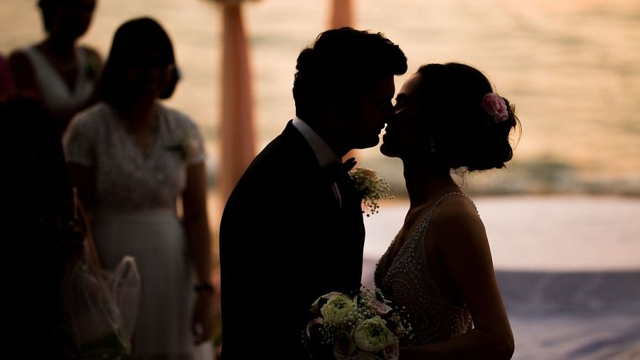 image of the couple sharing a kiss with a beautiful beach in the background - Maikhao Dream Villa Resort & Spa, Phuket