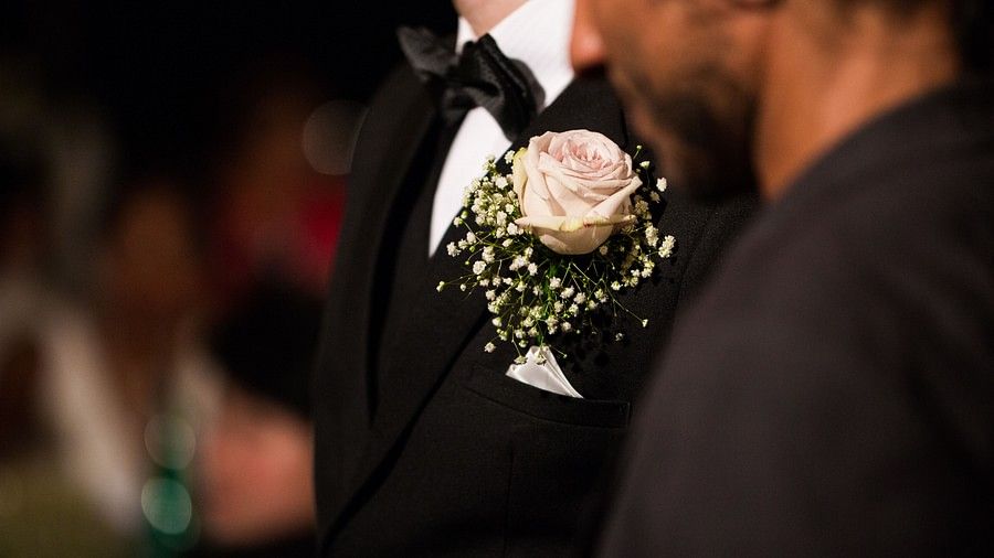 a close up image of a flower corsage tucked inside the pocket of a black tuxedo - Maikhao Dream Villa Resort & Spa, Phuket