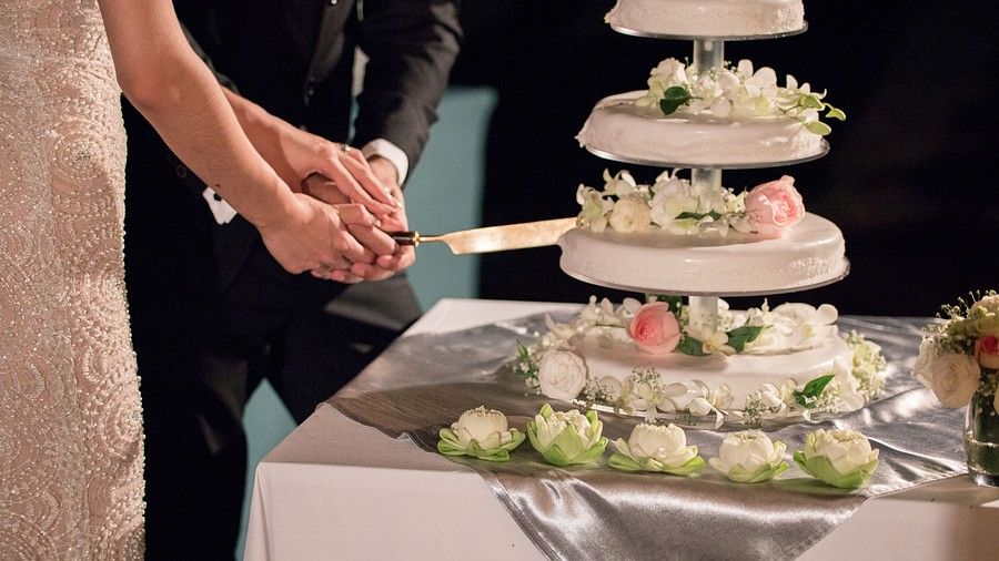 a close up image of the couple cutting the white wedding cake with a knife - Maikhao Dream Villa Resort & Spa, Phuket