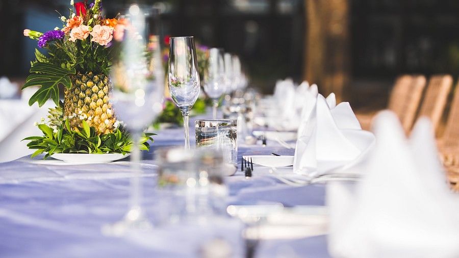 close up image of the dining table with well set glassware and crockery with flowers in the middle at maikhao dream villa resort & spa, phuket