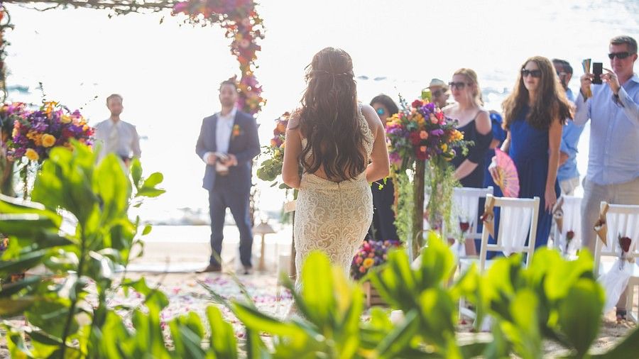 image of the bride walking down the aisle towards the groom with guests standing in the background - Maikhao Dream Villa Resort & Spa, Phuket