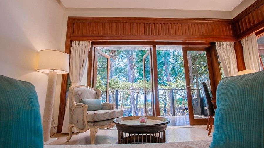 image showcasing an armchair in front of a coffee table with french windows in the back - two bedroom private pool beachfront villa