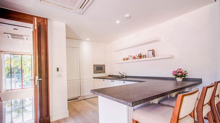 image of an L-shaped kitchenette along with three chairs lined near the counter - three bedroom private pool villa