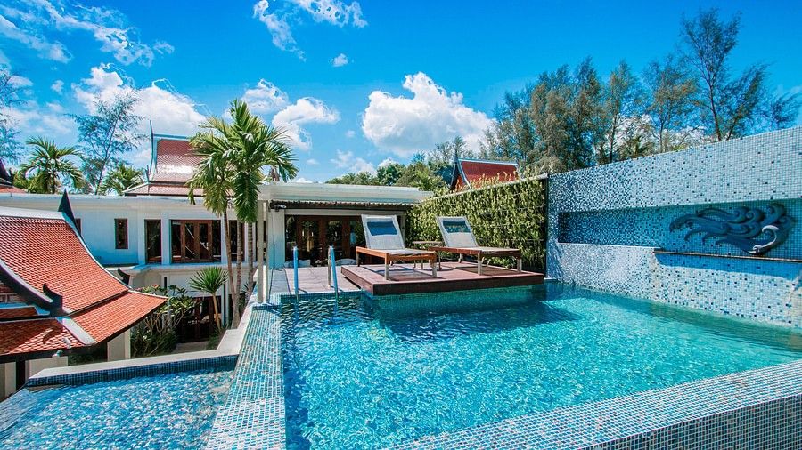 image featuring two sun loungers in front of an infinity pool on a bright day - three bedroom private pool villa