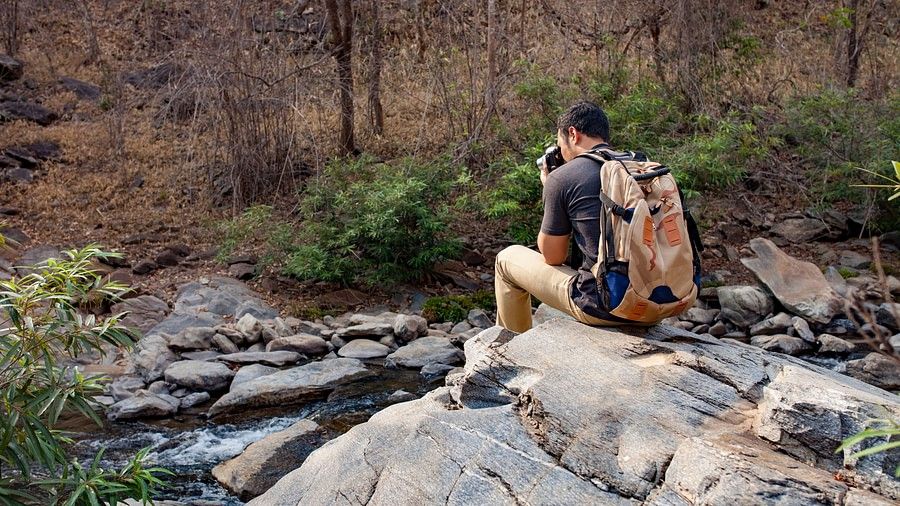 Two people hiking through a rocky, wooded area.