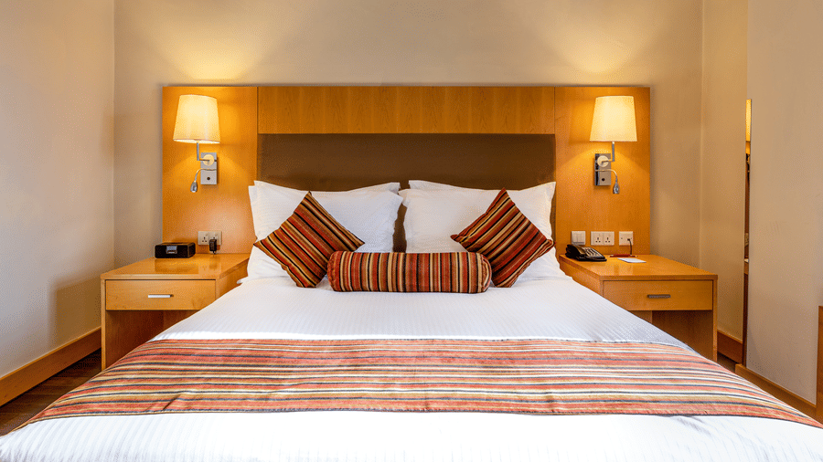 A suite featuring a double bed with striped accents, ambient lighting, and wooden furnishings—perfect for travellers seeking elegant suites in Addis Ababa.