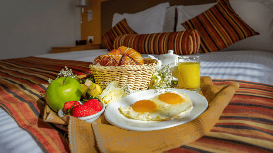 A close up shot of a tray containing many breakfast items that is placed on a bed - Ramada by Wyndham Addis, Addis Ababa.