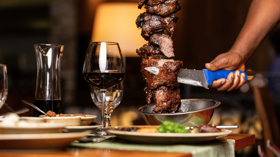 A close up of a staff slicing meat on a skewer on the table inside a restaurant - Ramada by Wyndham Addis, Addis Ababa.
