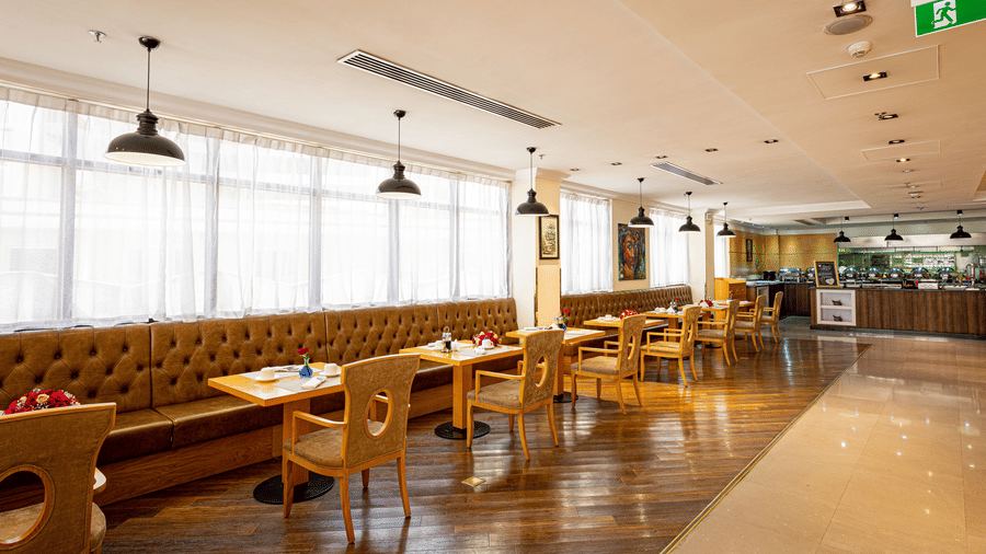 An overview of the many chairs, long sofa and tables inside a restaurant - Ramada by Wyndham Addis, Addis Ababa.