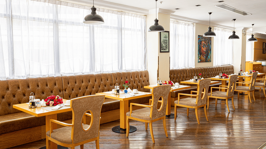 An overview of the many chairs, long sofa and tables inside a restaurant - Ramada by Wyndham Addis, Addis Ababa.