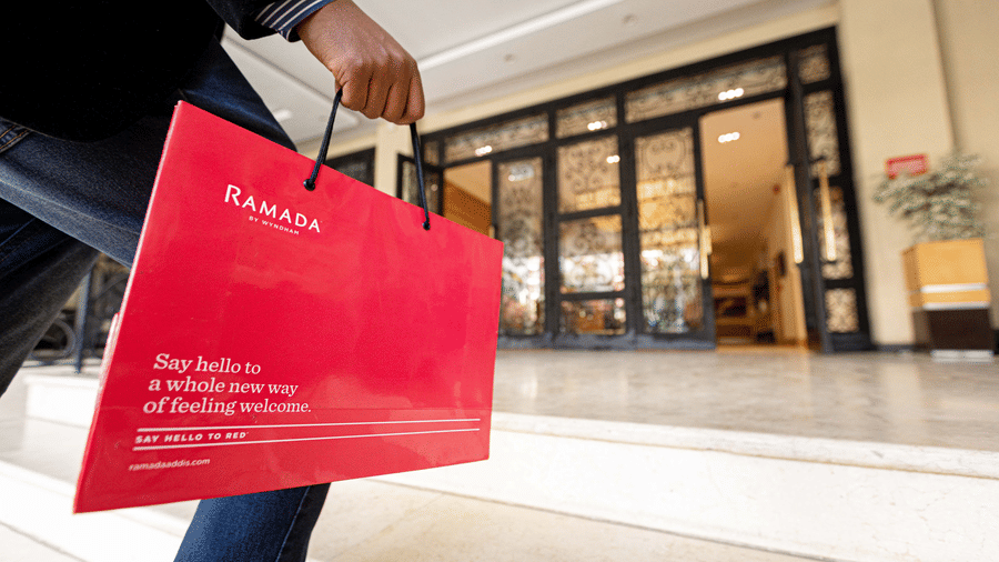 A close up shot of a person carrying a placard of Ramada Hotel while walking up the steps - Ramada by Wyndham Addis, Addis Ababa.