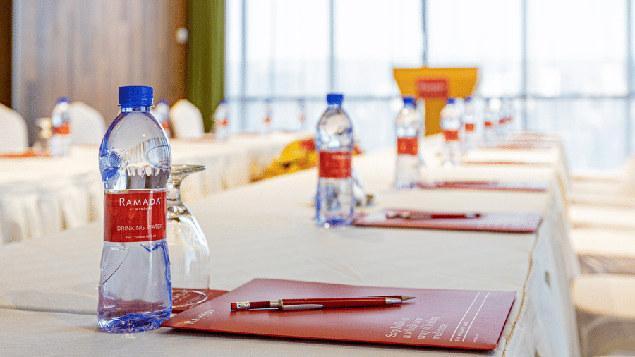 A close up shot of a meeting room with a U-shaped table with water bottles and a book on it and chairs in view - Ramada by Wyndham Addis, Addis Ababa.