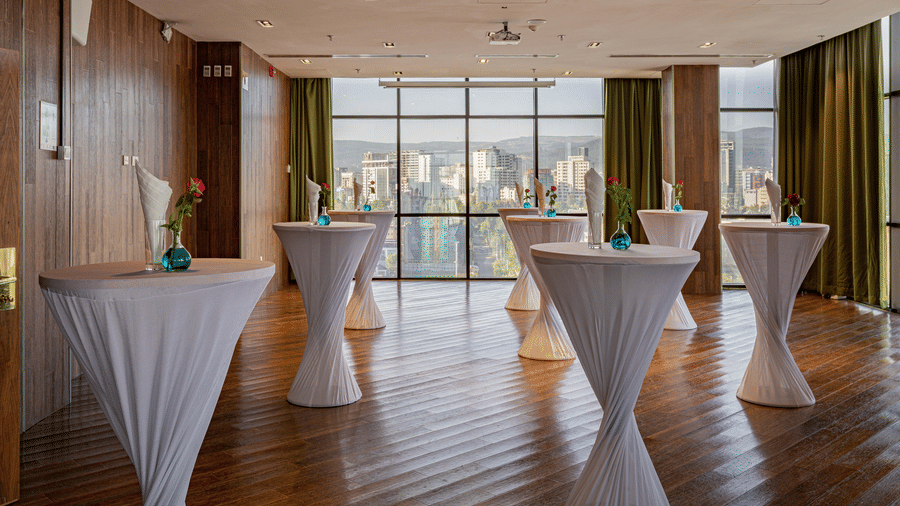 An overview of a event space with many round tables having a vase on it inside - Ramada by Wyndham Addis, Addis Ababa.