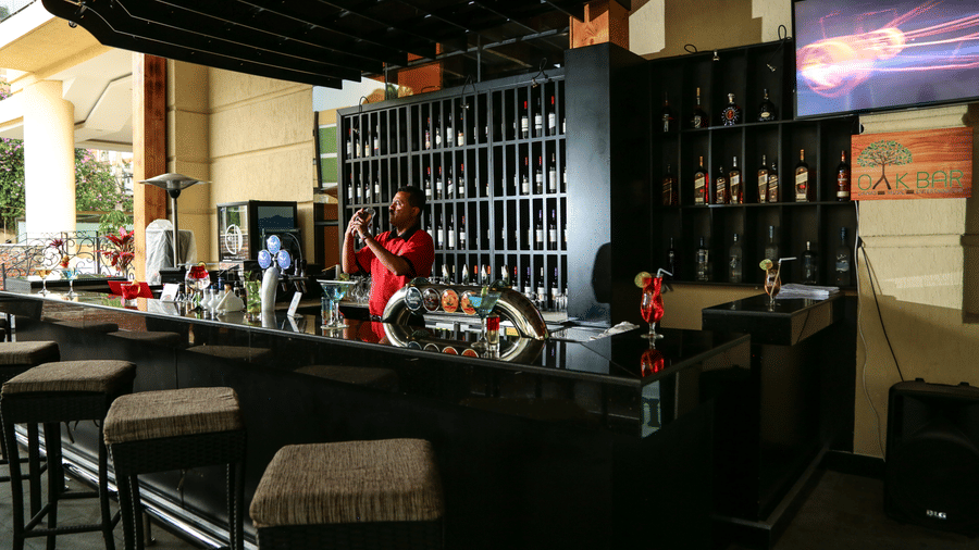 An overview of the bar area inside Ramada by Wyndham Addis, Addis Ababa with a bartender mixing drinks behind the counter.