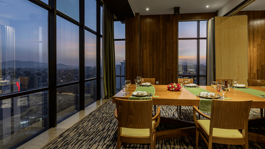An overview of the dining table placed next to a large floor to ceiling window inside FOGO NO CHÃO - Ramada by Wyndham Addis, Addis Ababa