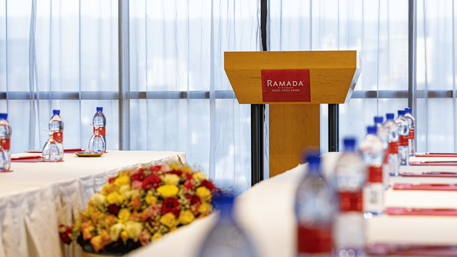 A view from the table having books and water bottles, of the podium in the meeting room - Ramada by Wyndham Addis, Addis Ababa.