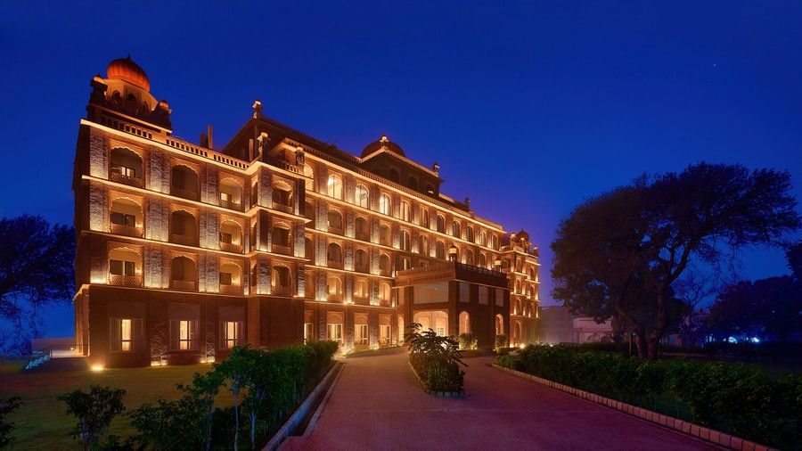 An evening view of our hotel in Amritsar illuminated warm yellow lights and dark blue sky in the background - Sarovar Premiere Amritsar