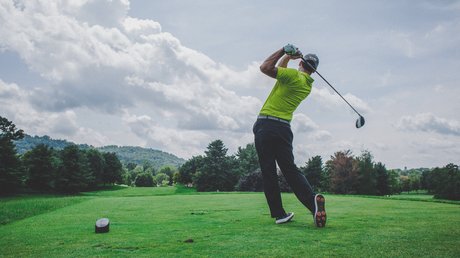 A view of a golfer after the swing, looking at the ball flying in the golf course filled with trees, one of the Chikmagalur packages at The Serai
