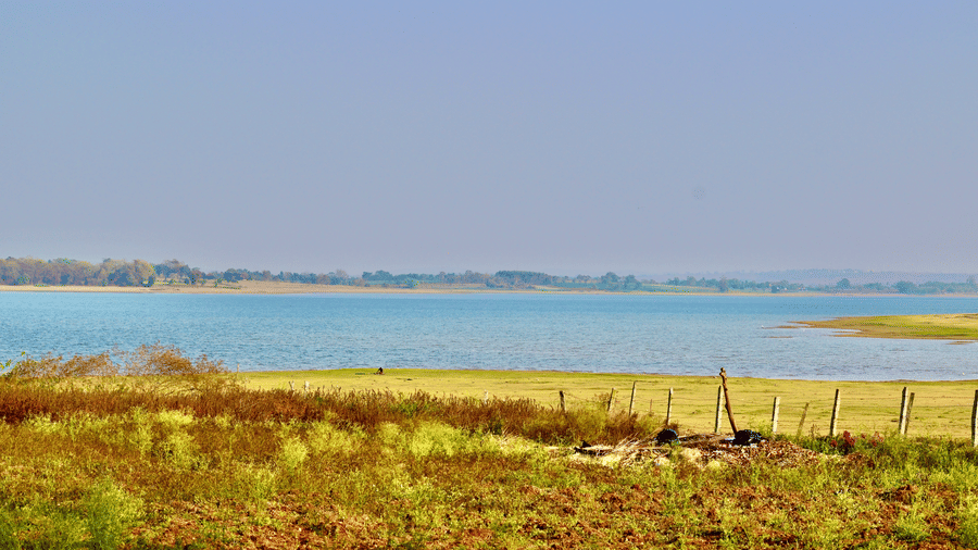 A view of the Kabini lake with grass in the foreground and another piece of land in the background